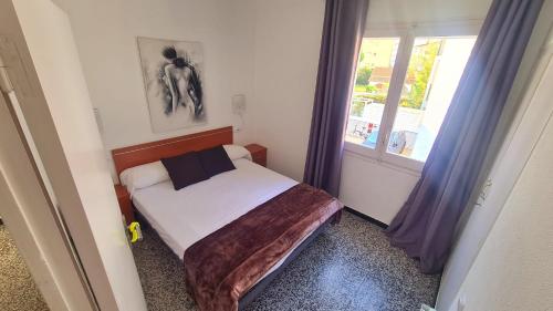 um pequeno quarto com uma cama e uma janela em Apartament Santa Margarida em Roses