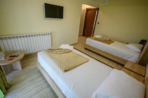 a room with two beds and a table and a television at Hotel Austin Ov in Ovidiu
