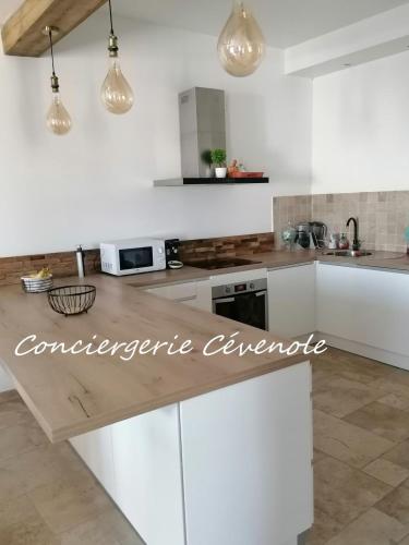 une cuisine avec des armoires blanches et un comptoir dans l'établissement Les Bosquets, à Alès