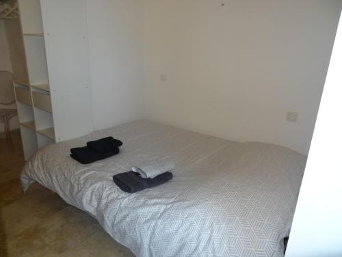 a bed with two black slippers and towels on it at Les Bosquets in Alès