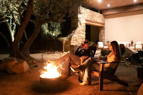 a man and a woman sitting around a fire at Hábimo - Valle de Guadalupe in Valle de Guadalupe
