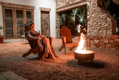a woman sitting in a chair next to a fire at Hábimo - Valle de Guadalupe in Valle de Guadalupe