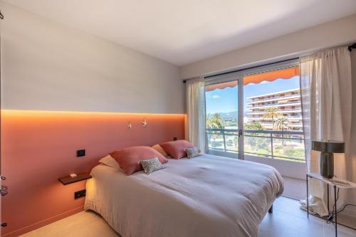 une chambre avec un grand lit et une grande fenêtre dans l'établissement Les Belles Terres - Résidence avec piscine vue mer, à Nice