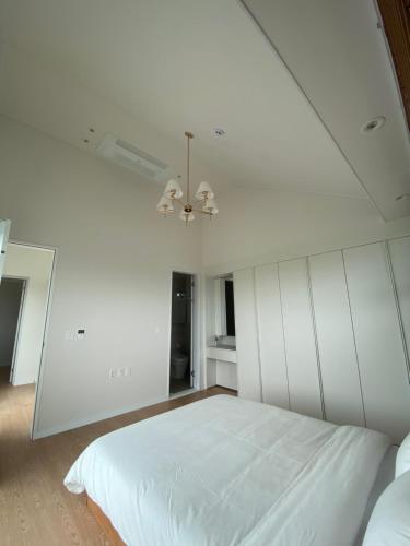 a bedroom with a white bed and a ceiling at Opera Garden in Seogwipo