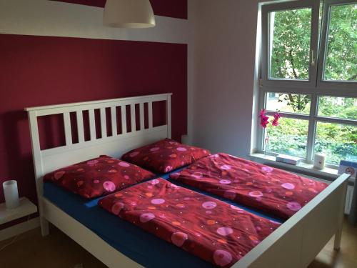 una camera da letto con due letti con lenzuola rosse e una finestra di Leipzig City Appartments a Lipsia