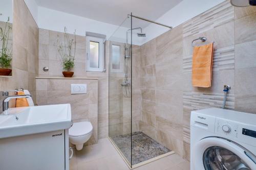a bathroom with a shower toilet and a washing machine at Deja near centar and Čikat bay with private parking in Mali Lošinj