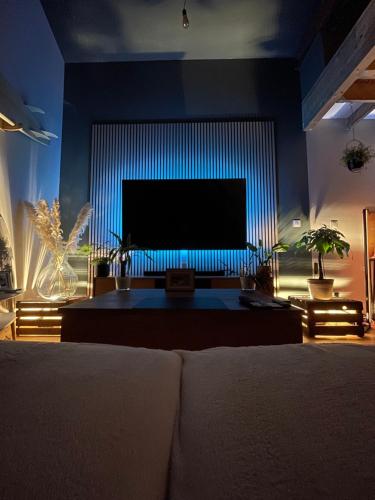 a living room with a large screen television at Loft industriel 150 m2 10min du circuit in Le Mans