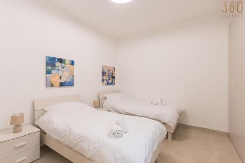 two beds in a bedroom with white walls at Stunning 3BR home in Gozo with access to pool by 360 Estates in Xagħra