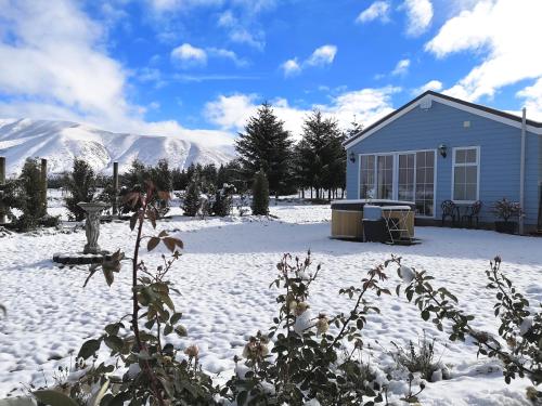 a house in the snow with mountains in the background at Kahurangi Cottage Twizel in Twizel