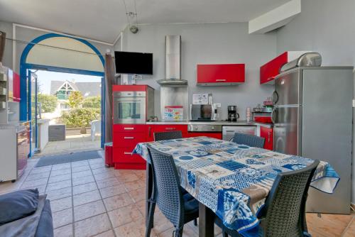 une cuisine avec une table, des chaises et des armoires rouges dans l'établissement Jahier Appartement Croisic, au Croisic