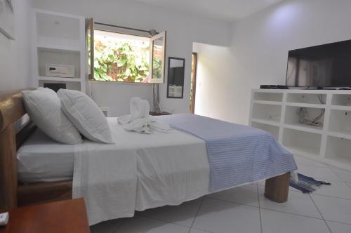a bedroom with a bed with white sheets and a window at Pousada Caminho da Praia in Jericoacoara