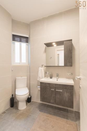 a bathroom with a white toilet and a sink at Stunning 3BR home in Gozo with access to pool by 360 Estates in Xagħra