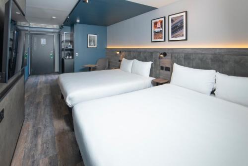 two beds in a room with blue walls at ibis Styles London Gatwick Airport in Crawley