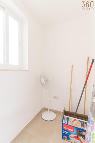 a room with a white wall and a fan at Stunning 3BR home in Gozo with access to pool by 360 Estates in Xagħra