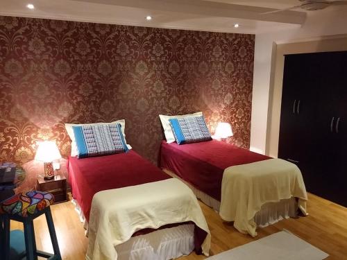 a bedroom with two beds with red and white sheets at Casa 24 Puerto Iguazu in Puerto Iguazú
