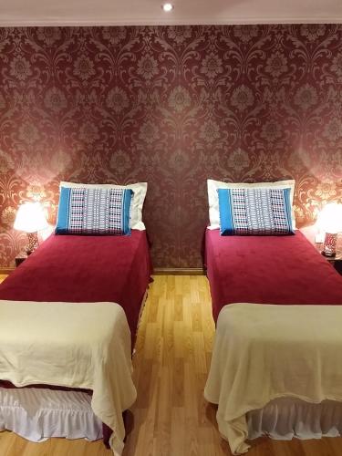 two beds in a room with red walls at Casa 24 Puerto Iguazu in Puerto Iguazú