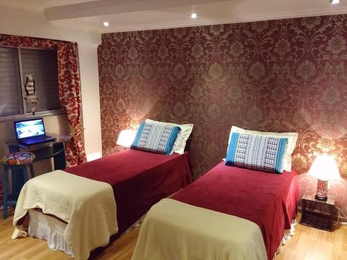 two beds in a room with red walls at Casa 24 Puerto Iguazu in Puerto Iguazú