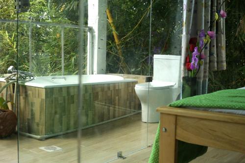 a bathroom with a bath tub and a toilet at Nkofu Forest Cottage - Kitende in Wakiso