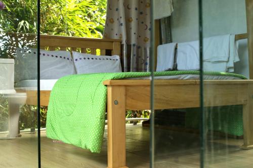 a wooden bench with a green blanket on it at Nkofu Forest Cottage - Kitende in Wakiso