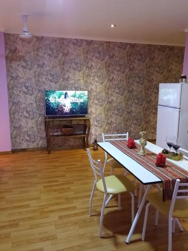 a dining room with a table and a tv on a wall at Casa 24 Puerto Iguazu in Puerto Iguazú