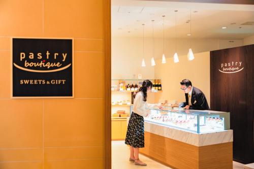 a woman standing at a counter in a pastry shop at Hotel Okura Fukuoka in Fukuoka
