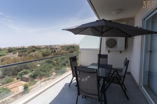 a table and chairs with an umbrella on a balcony at Stunning 3BR home in Gozo with access to pool by 360 Estates in Xagħra