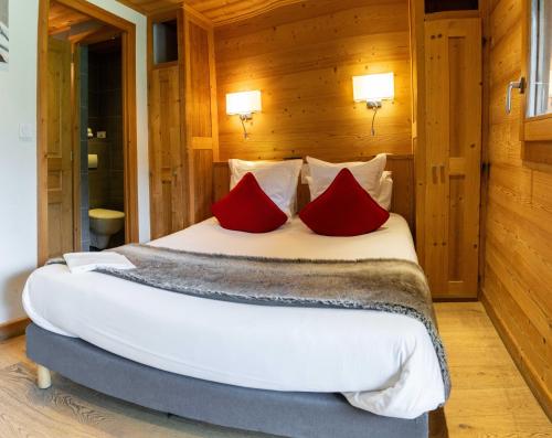 a bedroom with a large bed with red pillows at Les Chalets d'Adelphine & SPA in Les Gets