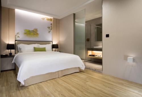 ein Schlafzimmer mit einem großen weißen Bett und einem großen Spiegel in der Unterkunft 星鑽國際商旅 編號315 in Tainan