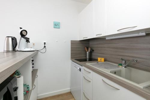 ル・クロワジックにあるPetite maison -の白いキャビネットとシンクのあるキッチン