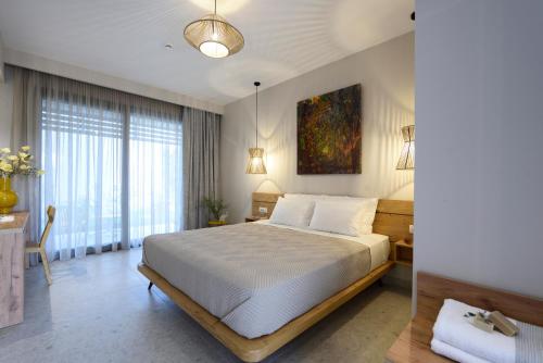 a bedroom with a large bed in a room with windows at Falena Luxury Rooms in Kalyves Poligirou