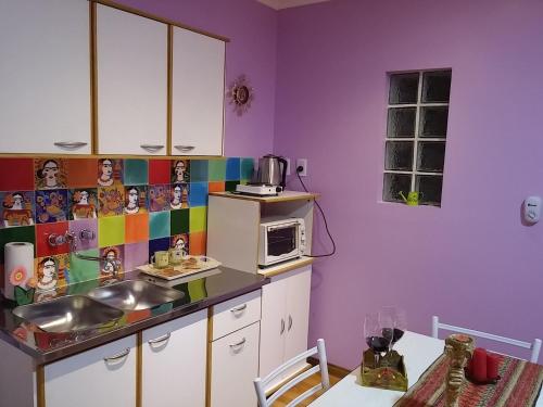 a kitchen with purple walls and a counter with a microwave at Casa 24 Puerto Iguazu in Puerto Iguazú