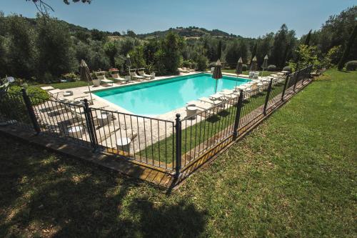una valla alrededor de una piscina con sillas y sombrillas en Relais Ciavatta Country Hotel, en Montemerano