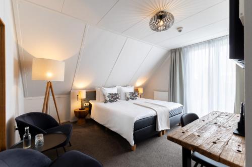 um quarto de hotel com uma cama, uma mesa e cadeiras em Boutique Hotel Texel em De Cocksdorp