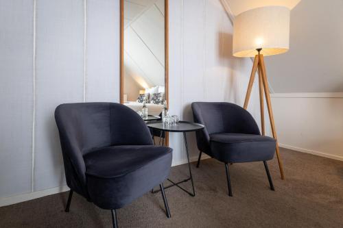 a room with two chairs and a table and a lamp at Boutique Hotel Texel in De Cocksdorp