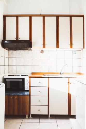 a kitchen with white cabinets and a microwave at Gk Suites-Constantin view , auto check-in 24h in Larisa
