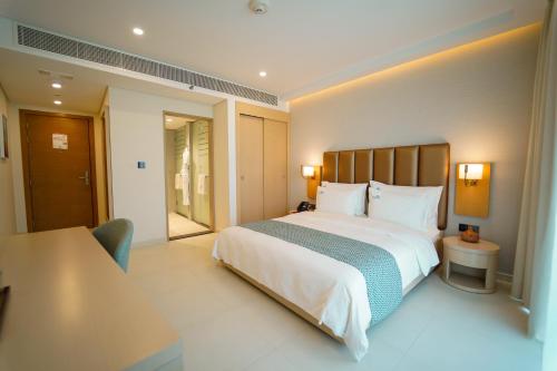 Un dormitorio con una gran cama blanca y una mesa en Zoya Health & Wellbeing Resort, en Ajman