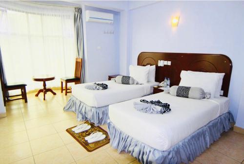 a hotel room with two beds and a table at Green Mountain Hotel in Arusha