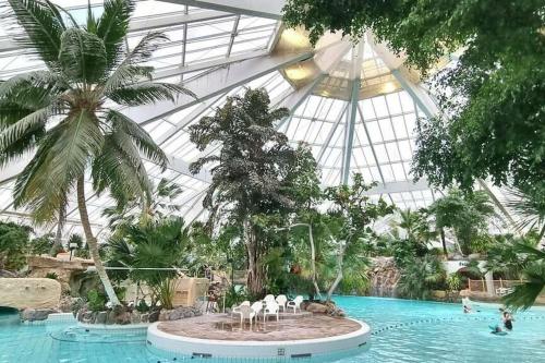 a pool with white chairs in the middle of a garden at Douceur de vivre au bord de l'Avre in Chennebrun