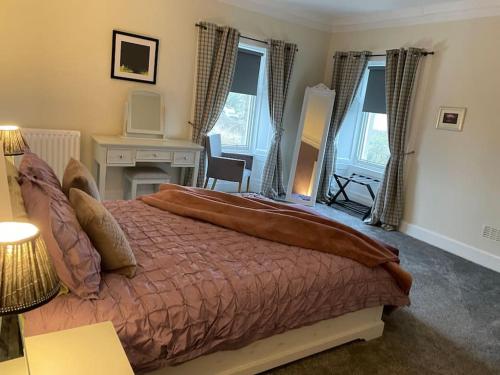 a bedroom with a large bed with a desk and windows at Bridge Holiday Let in Linlithgow