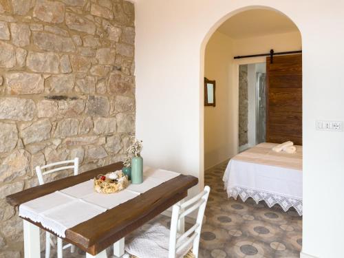 a table and chairs in a room with a stone wall at La casa di nonna Pietra in Baunei