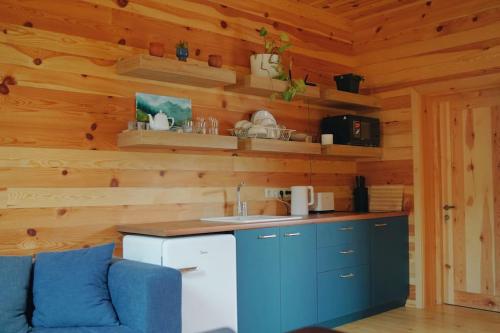 a kitchen with blue cabinets and a blue couch in a cabin at Elegant pet-friendly double villa, perfect for couples Svaneti Countryside 4 in Mestia