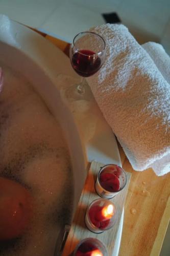 a glass of wine sitting next to a bathtub with a glass of wine at Elegant pet-friendly double villa, perfect for couples Svaneti Countryside 4 in Mestia