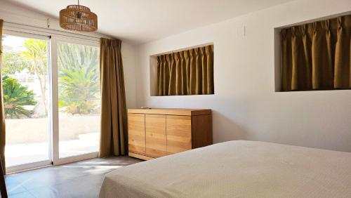 1 dormitorio con 1 cama, vestidor y ventana en Villa las palmeras, en Benissa
