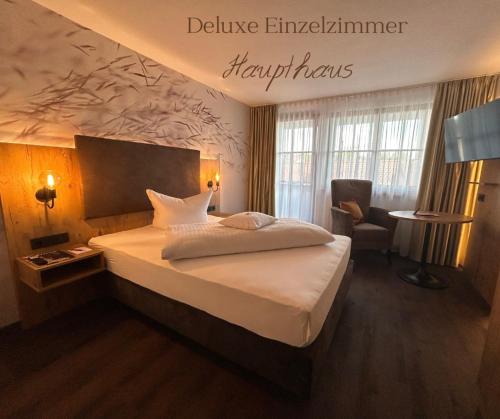 a hotel room with a bed and a chair at Hotel Schwaiger in Glonn