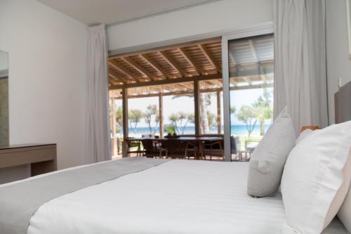 a bedroom with a bed and a view of the ocean at Elya Beach Luxury Suites in Ayios Theodhoros