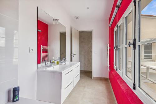 La salle de bains est pourvue d'un lavabo blanc et d'un mur rouge. dans l'établissement Appartement de Messugues - Appt standing vue mer, à Saint-Raphaël