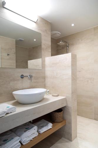 a bathroom with a white sink and a mirror at Elya Beach Luxury Suites in Ayios Theodhoros