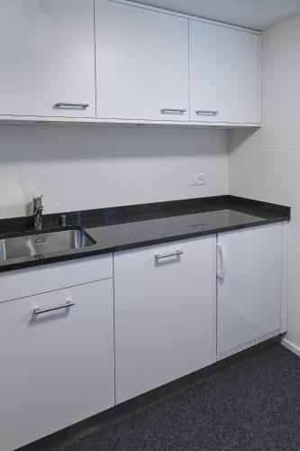 a white kitchen with a sink and white cabinets at Hotel Jäger Jeuss - Murten - Self-Check-in in Jeuss