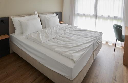 a large white bed with white sheets and pillows at Hotel Jäger Jeuss - Murten - Self-Check-in in Jeuss