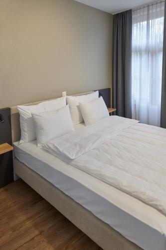 a large bed with white sheets and pillows at Hotel Jäger Jeuss - Murten - Self-Check-in in Jeuss